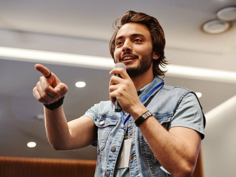 Ragazzo in abiti casual con il microfono in mano che coinvolge il pubblico